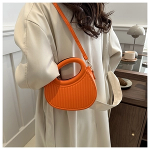 Vue détaillée du sac demi-lune plissé en cuir PU orange vif porté par un mannequin