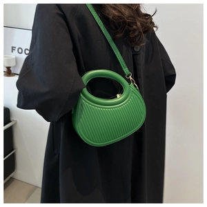 Close-up of green crescent bag featuring unique vertical pleated texture and hollow handle