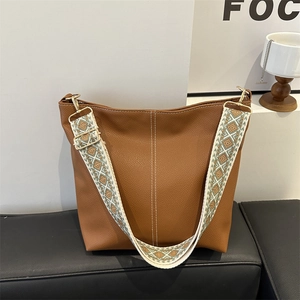 Brown litchi texture bucket bag with wide ethnic geometric shoulder strap and gold hardware