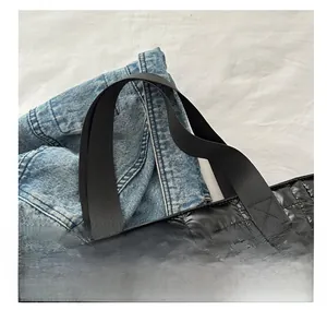 Detalle de las asas de lona reforzadas y costuras acolchadas en un bolso grande negro