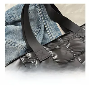 Detalle del asa reforzada con costuras cruzadas y hebilla metálica en bolso negro