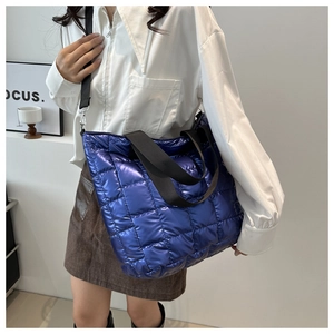 Primer plano del bolso tote azul metalizado acolchado con asas y correa ajustable
