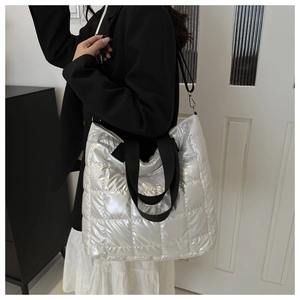 Detalle del bolso tote acolchado plateado con acabado metálico y asas anchas negras