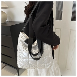 Detalle del bolso tote plateado acolchado con asas negras y textura de rejilla suave