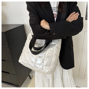 Detalle del bolso tote acolchado plateado con textura metálica y correas negras