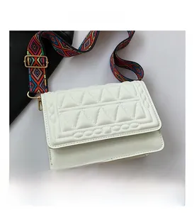 Detail of white quilted handbag featuring 3D triangle texture and bohemian woven strap