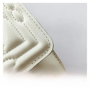 Close-up of white quilted faux leather material with elegant diamond lattice stitching