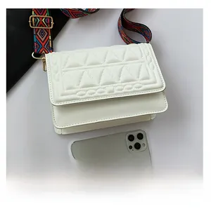 Detail of white quilted crossbody bag with ethnic jacquard strap and gold hardware