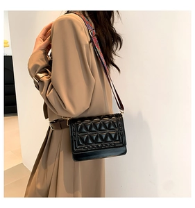 Detail of black 3D quilted crossbody bag with bohemian patterned wide shoulder strap