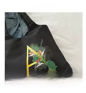 Gros plan sur un cabas noir avec lettre A fleurie et motif d'oiseau du paradis