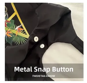 Détail d'un fermoir magnétique en métal sur un sac fourre-tout noir à motif floral