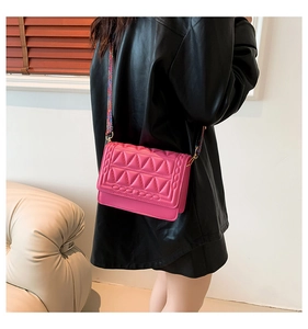 Close-up of hot pink quilted crossbody bag with colorful woven wide shoulder strap