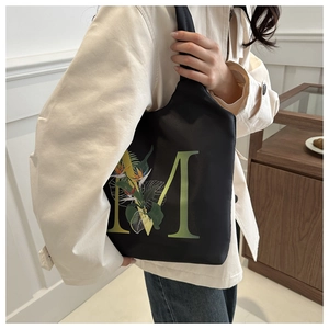 Détail d'un sac cabas noir avec imprimé floral 'M' et larges bandoulières confortables