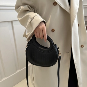 Sac à main croissant noir chic avec textures verticales et détails dorés sur modèle