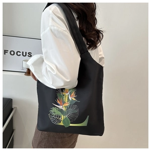 Détail du sac cabas noir avec imprimé floral tropical et design de lettre L