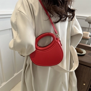 Sac demi-lune rouge à rayures verticales en relief porté à l'épaule par un mannequin
