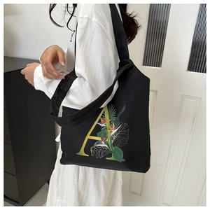 Détail d'un sac cabas tendance avec lettre A en dégradé jaune et imprimé floral