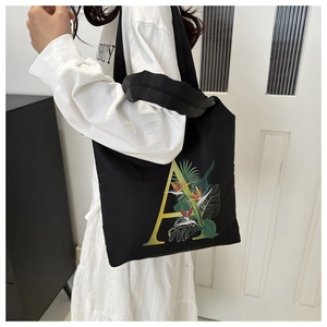 Détail du sac cabas en toile noire avec lettre A jaune et motif de fleurs tropicales