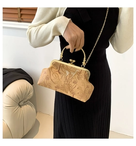 Dettaglio della pochette vintage beige con rilievo floreale e chiusura in metallo oro