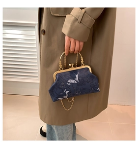 Dettaglio borsa blu navy con ricamo floreale e tracolla a catena in metallo oro