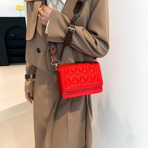 Red quilted crossbody square bag with colorful woven shoulder strap worn by a model
