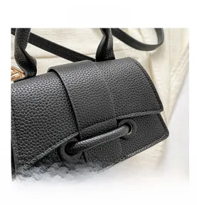 Gros plan du mini sac noir en cuir grainé litchi avec détails métalliques dorés