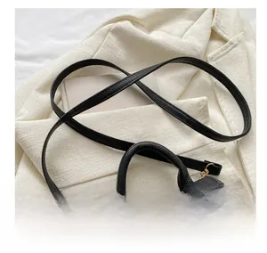 Gros plan du sac en cuir noir grainé avec bandoulière réglable et détails dorés fins