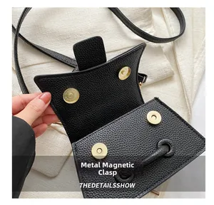 Détail du sac en cuir noir grainé litchi montrant les fermoirs magnétiques dorés