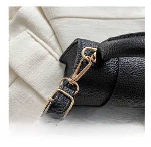 Gros plan sur le crochet doré et la boucle en métal d'un sac noir en cuir grainé lychee