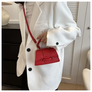 Détail d'un sac à main rouge en cuir grainé avec rabat et bandoulière amovible