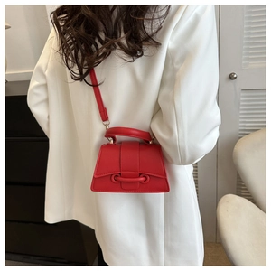 Détail du sac à main en cuir rouge sur costume blanc avec base incurvée élégante