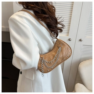 Brown crocodile pattern crescent bag with silver chains worn by model in white suit