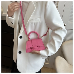 Gros plan d'un sac à main fuchsia en cuir litchi porté avec un blazer blanc élégant