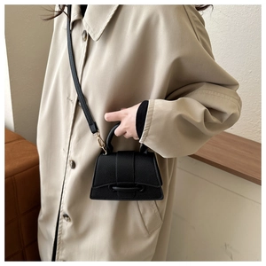 Détail du sac à main en cuir grainé noir avec boucle unique et poignée élégante en haut