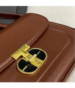 Dettaglio della chiusura in metallo dorato e pelle marrone su borsa a tracolla alla moda