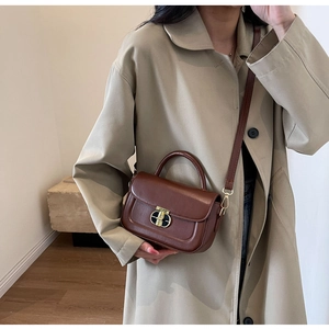 Borsa a tracolla marrone con chiusura in metallo in un ambiente interno alla moda