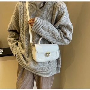 Dettaglio mini borsa bianca a tracolla con chiusura in metallo su maglione lavorato