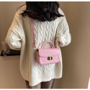 Dettaglio borsa a tracolla rosa in pelle con chiusura in metallo ovale e manico elegante