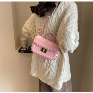 Dettaglio della borsa a tracolla rosa con fibbia dorata e pelle su un maglione a maglia
