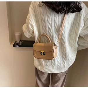 Dettaglio elegante borsa in pelle albicocca con chiusura a T dorata e manico superiore