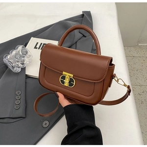 Dettaglio borsa in pelle marrone con chiusura a scatto dorata e manico superiore fisso