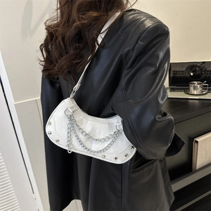 White crescent underarm bag with silver chains and rivets on a black leather jacket