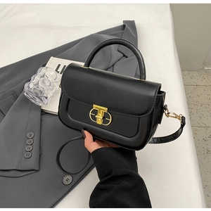 Dettaglio della borsa a tracolla in pelle nera con elegante chiusura geometrica in metallo oro