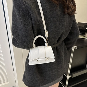 Sac à main chic en cuir litchi blanc avec bandoulière porté sur un blazer en laine