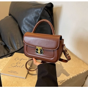 Dettaglio di borsa a mano vintage in pelle marrone con chiusura dorata su base di pietra