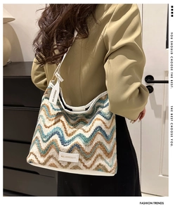 Detail of bohemian knit bucket bag with blue wave pattern and leather shoulder strap