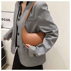 Détail d'un sac bandoulière demi-lune en similicuir marron avec boucles en métal doré