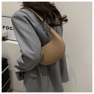 Détail du sac à bandoulière demi-lune kaki porté par un mannequin au design minimaliste en cuir