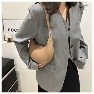Détail d'un sac d'épaule demi-lune en cuir mat beige au design minimaliste
