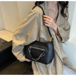 Detail of black pebbled PU leather crossbody bag with decorative gold chain and zipper